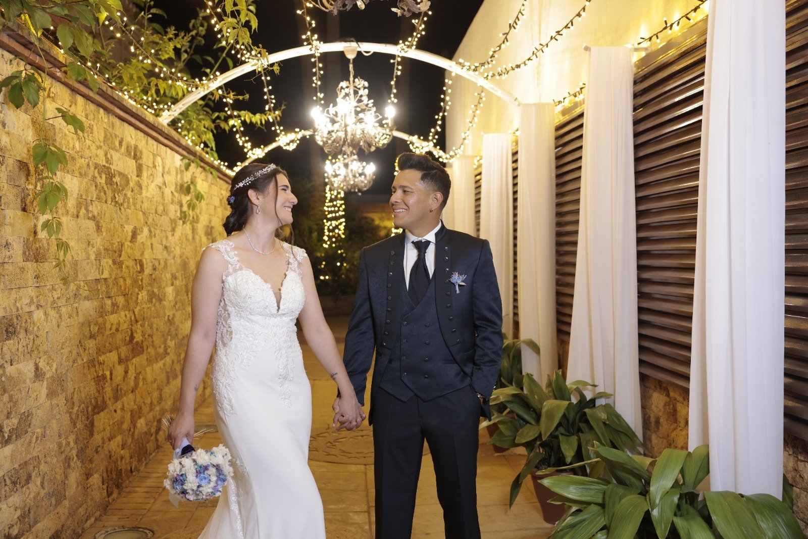 Pareja de novios caminando bajo luces en una boda organizada por Mareli Eventos